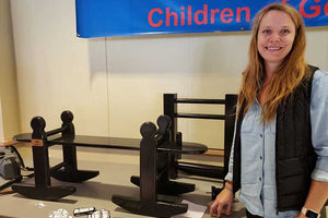 Kristi Outland, part owner of The Joggle Factory, posing next to a child size joggling board.