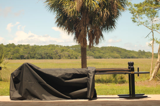 A 10' Charleston green joggling board with a black cushion.  The 10' joggling board is halfway covered by an outdoor cover.  The joggling board is overlooking the marsh on Edisto Island, SC.