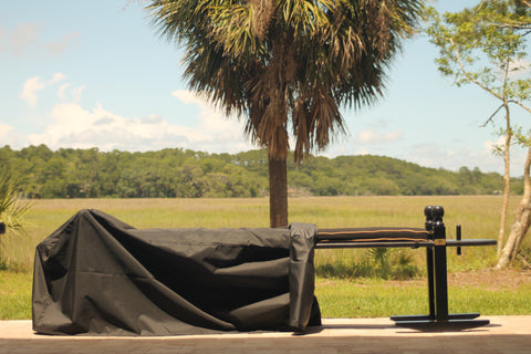 A 10' Charleston green joggling board with a black cushion.  The 10' joggling board is halfway covered by an outdoor cover.  The joggling board is overlooking the marsh on Edisto Island, SC.