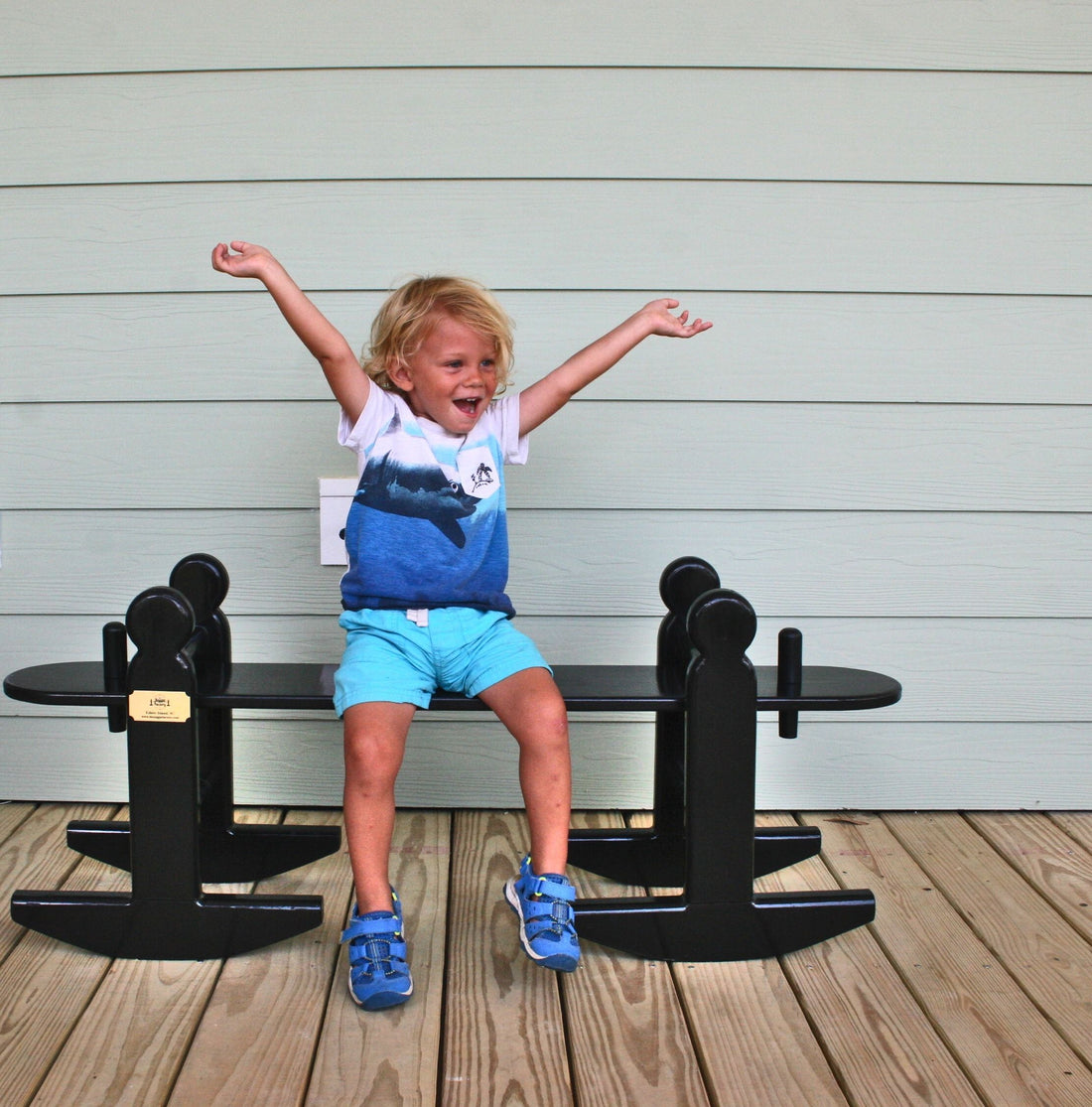 A cute little boy in blue rocking side to side on his children's joggling board.