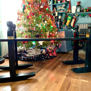 A beautifully Christmas themed decorated living room with fire place, stockings hung, brightly lit Christmas tree with a 6' Charleston green joggling board waiting to be opened by the tree.