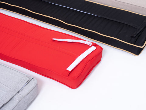 Close up view of joggling board cushions with velcro closure, showing colors of tan, black, red and grey on white background.