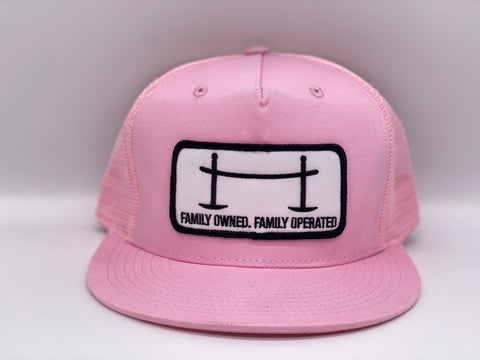 Front view of The Joggle Factory pink trucker hat with patch reading Family Owned Family Operated.