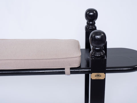 Rocker view of a joggling board with a tan cushion and brass plaque on white background.